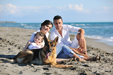 Image showing happy family playing with dog on beach