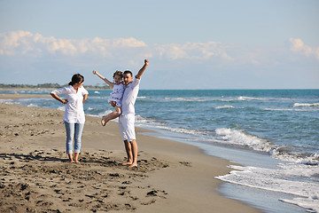 Image showing happy family playing with dog on beach