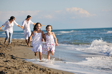 Image showing happy family playing with dog on beach