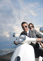 Image showing just married couple on the beach ride white scooter