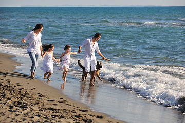 Image showing happy family playing with dog on beach