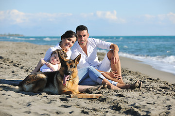 Image showing happy family playing with dog on beach