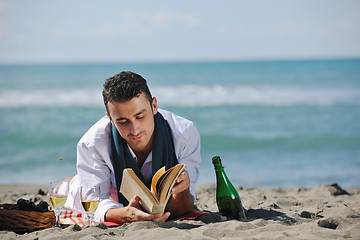 Image showing man reading book at beach