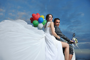 Image showing just married couple on the beach ride white scooter