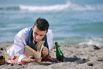 Image showing man reading book at beach