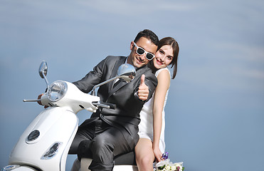 Image showing just married couple on the beach ride white scooter