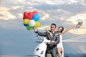 Image showing just married couple on the beach ride white scooter