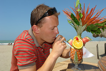 Image showing the man drinking a coctail on the beach of pacific ocean