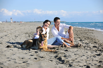 Image showing happy family playing with dog on beach