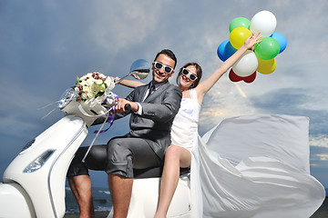 Image showing just married couple on the beach ride white scooter