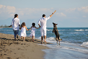 Image showing happy family playing with dog on beach