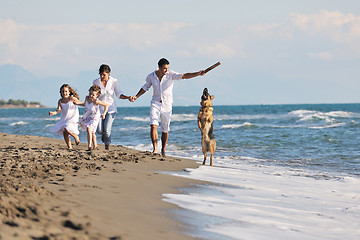 Image showing happy family playing with dog on beach