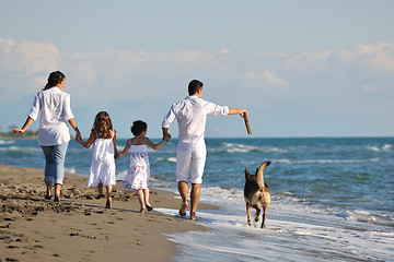 Image showing happy family playing with dog on beach