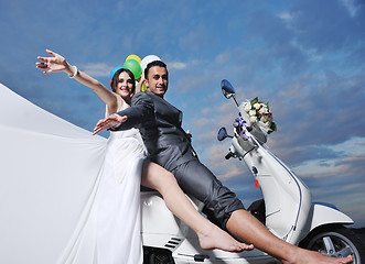 Image showing just married couple on the beach ride white scooter