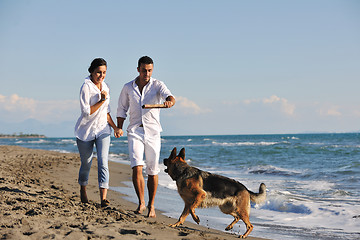 Image showing happy family playing with dog on beach