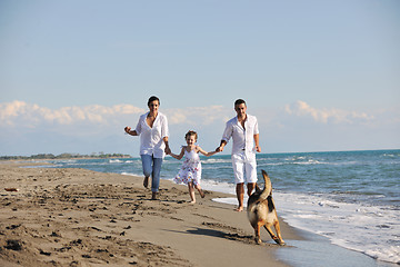 Image showing happy family playing with dog on beach