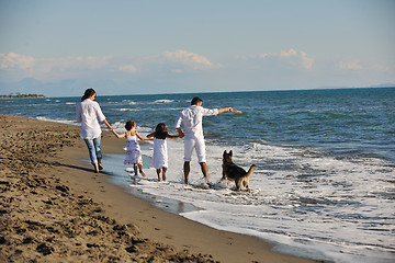 Image showing happy family playing with dog on beach