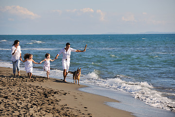 Image showing happy family playing with dog on beach