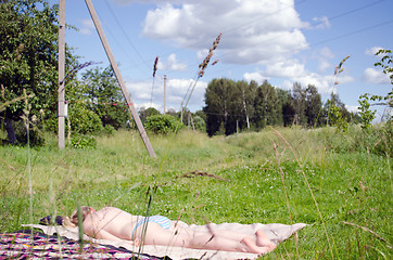 Image showing Half nude woman  sunbathing plaid in rural meadow 