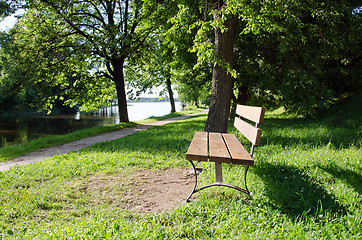 Image showing Wooden bench near lake resort. Path between trees 