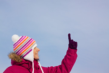 Image showing Pretty girl in witer clothes pointing upwards