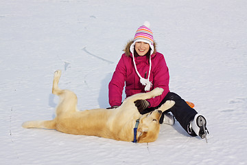 Image showing Girl on ice skates playing with dog