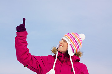 Image showing Pretty girl in witer clothes pointing upwards