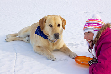 Image showing Girl laying with dog in snow