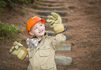 Image showing Adorable Child Boy with Big Gloves Playing Handyman Outside