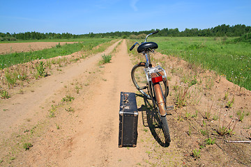 Image showing old valise near old bicycle on rural road