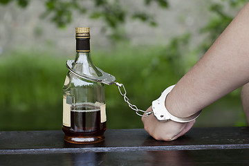 Image showing 	Man in handcuffs interconnected with a bottle of alcohol