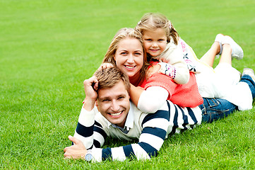Image showing Smiling family of three piled on top of each other