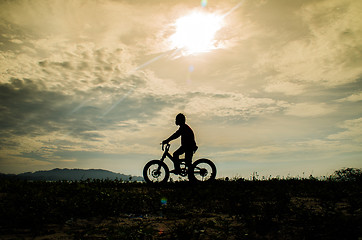 Image showing Silhouette of kid riding a bicycle