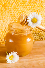 Image showing jar of honey on the background of honeycombs 