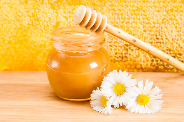 Image showing jar of honey on the background of honeycombs 