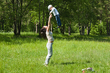 Image showing Mother raising her little child up high