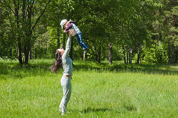 Image showing Mother raising her little child up high