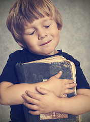 Image showing Little boy hugging an old book