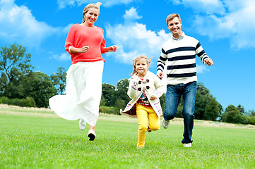 Image showing Young couple racing with their cute little daughter