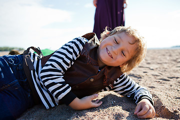 Image showing Smiling boy lying on the beach.