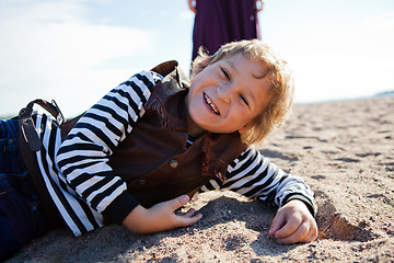 Image showing Smiling boy lying on the beach.