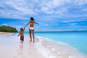 Image showing mom and son running on seashore