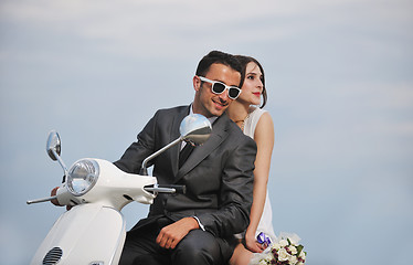 Image showing just married couple on the beach ride white scooter