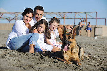 Image showing happy family playing with dog on beach