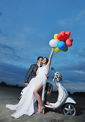 Image showing just married couple on the beach ride white scooter