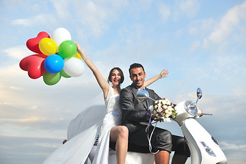 Image showing just married couple on the beach ride white scooter