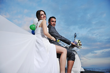 Image showing just married couple on the beach ride white scooter