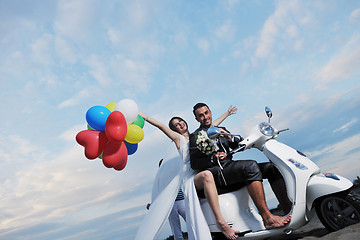 Image showing just married couple on the beach ride white scooter