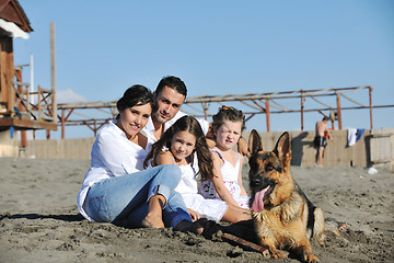 Image showing happy family playing with dog on beach