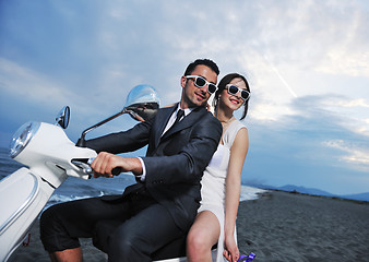 Image showing just married couple on the beach ride white scooter